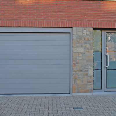 Sectionaalpoort in gelijnde Bumax panelen en voordeur voorzien van gezandstraald glas met klare boorden en lijnen