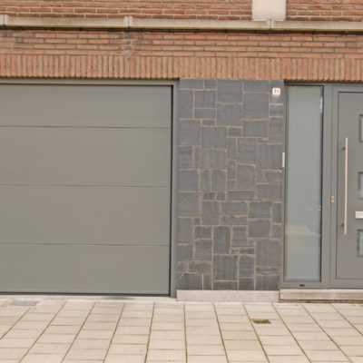 Sectionaalpoort in vlakke staalplaat panelen en aluminium voordeur met sierpaneel type Tristar